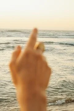 Soft focus. Reaching hand towards the ocean waves at sunset on a sandy beach. Stock Photos