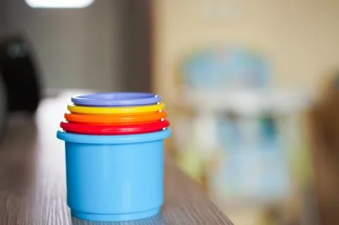 Soft focus shot of a stack of colorful plastic toy cups on a wooden table 库存照片