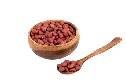 Soft focus on a spoon with peeled peanuts on a white background. Stock Photos