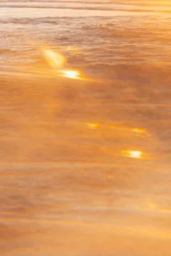 Soft focus. Sunset over ocean waves at beach with golden reflections during l Stock Photos