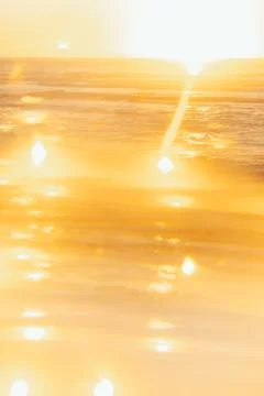 Soft focus. Sunset over ocean waves at beach with golden reflections during l Stock Photos