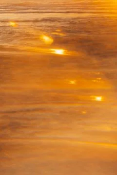 Soft focus. Sunset over ocean waves at beach with golden reflections during l Stock Photos
