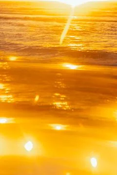 Soft focus. Sunset over ocean waves at beach with golden reflections during l Stock Photos