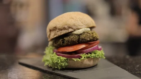 Soft Focus of Veggie Burger with Lettuce, Tomato and Onion on Dinner Balcony Stock Footage 128833127