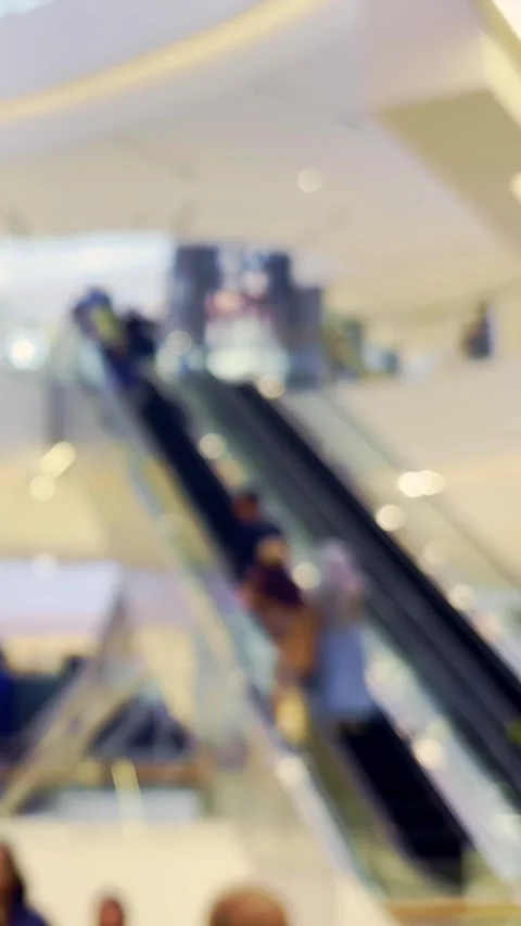 Soft focus view of shoppers and escalators inside a bright modern retail sh.. Video stock 340115986