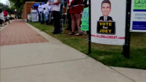 Soft focus of walk through line of election poll greeters, ending in focus Vídeo Stock 153346474