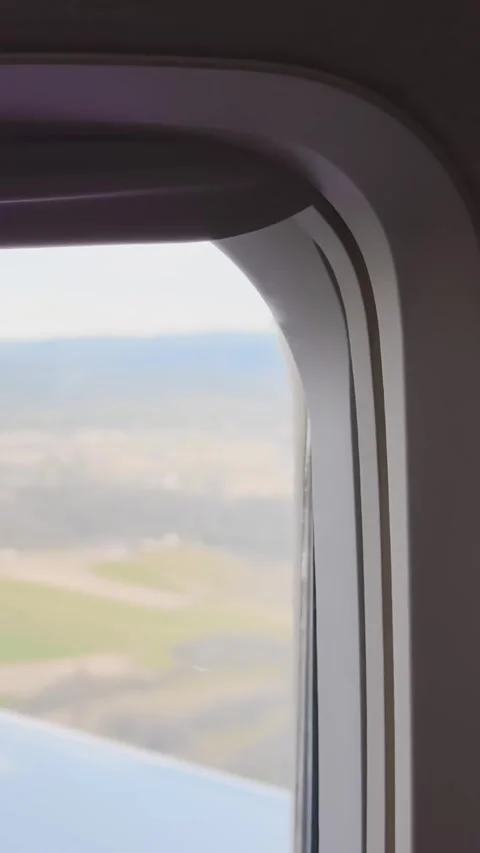 Soft-focused airplane window view during flight, with blurred wing, pale sky Stock Footage 337253242
