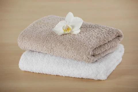 Soft folded towels with orchid flower on wooden table Stock Photos