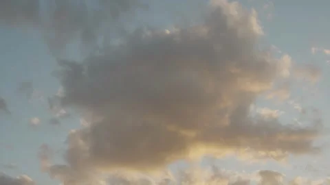 Soft golden clouds drifting slowly across a blue sunset sky Stock Footage 334627540