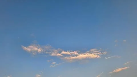 Soft Golden Clouds Floating in Clear Blue Sky Background with Copy Space Stock Photos