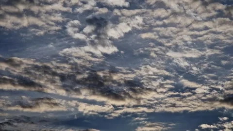 Soft golden hues of the setting sun break through scattered clouds Stock Footage 344811077