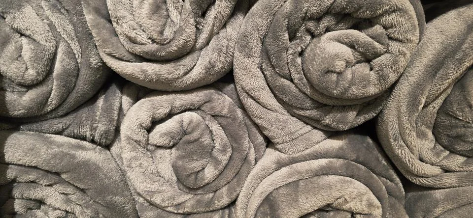 Soft gray rolled blankets stacked neatly for cozy home decor Stock Photos