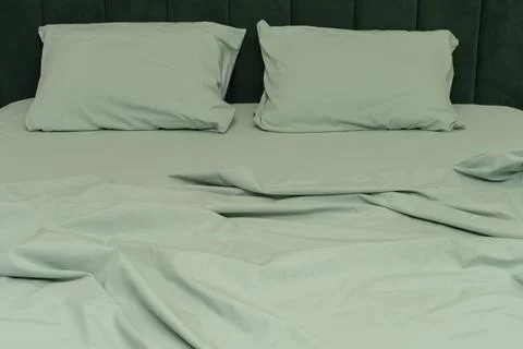 Soft green bedding with two pillows on a neatly made bed Stock Photos