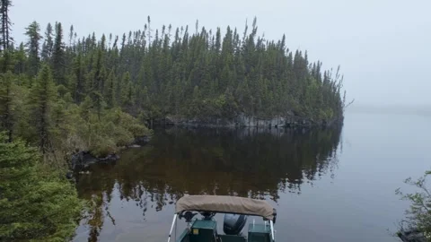 Soft grey light blankets the forest, boat and lake in a calm, misty atmosphere Stock Footage 333197206