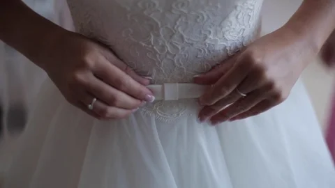 The soft hands of the bride are correcting the bow on the white wedding dress Stock Footage