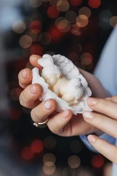 Soft hands cradle delicate white angel figurines Foto stock