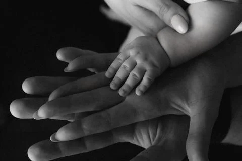 Soft hands cradle a tiny child's hand Foto stock