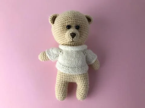 Soft knitted bear on a pink matte background. bear for a gift, a toy for chil Stock Photos