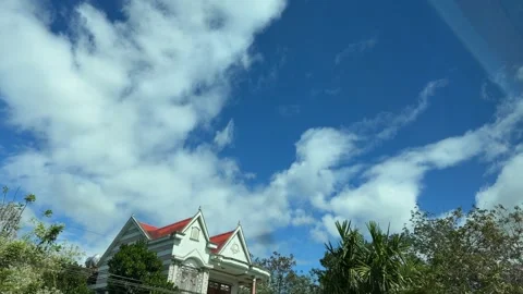 Soft layers of drifting clouds fill the upper frame while roadside trees slide Stock Footage 324839027