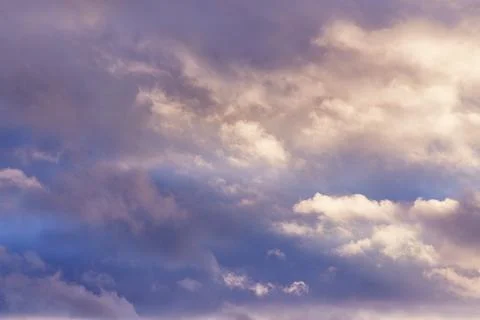 The soft light of the evening sun on the cumulus clouds in the sky Stock Photos