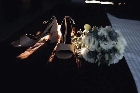Soft light highlights elegant shoes beside a delicate bouquet Foto stock