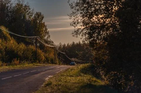 Soft light of the setting evening sun reflects on power lines along an asph.. Stock Photos