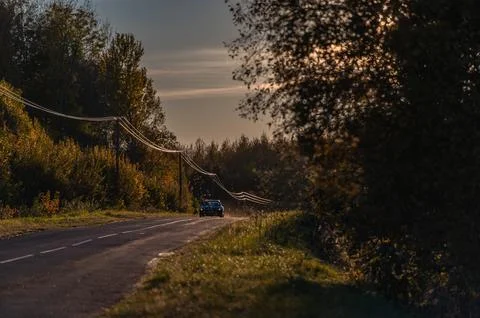 Soft light of the setting evening sun reflects on power lines along an asph.. Stock Photos