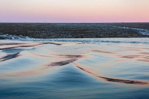 Soft, long water surface ripples in a pink and silber sunset light Stock Photos