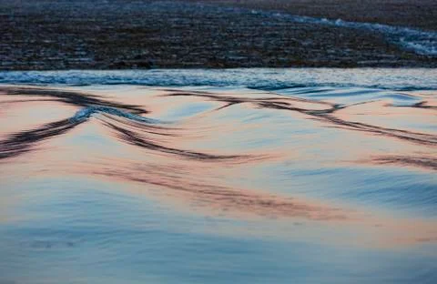 Soft, long water surface ripples in a pink and silber sunset light Foto stock