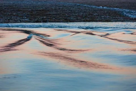 Soft, long water surface ripples in a pink and silber sunset light Foto stock