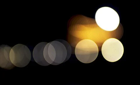 Soft luminous circles drift across a dark night scene, where warm golden and Foto stock