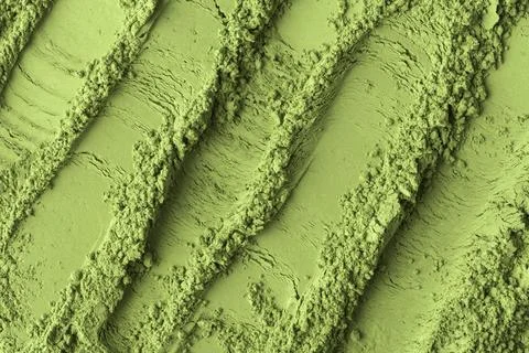 Soft matcha powder shaped into smooth curved lines, showing contrast between Фото