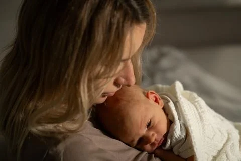 Soft moment shared between mother and baby during twilight in a cozy, serene Stock Photos