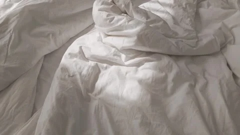 Soft morning sunlight casting shadows on wrinkled white cotton bedsheets 스톡 동영상 313256211
