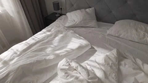 Soft morning sunlight casting shadows on wrinkled white cotton bedsheets 스톡 동영상 313256264