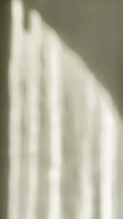 Soft morning sunlight casts undulating shadow across beige plaster wall evoking  스톡 동영상 333691108