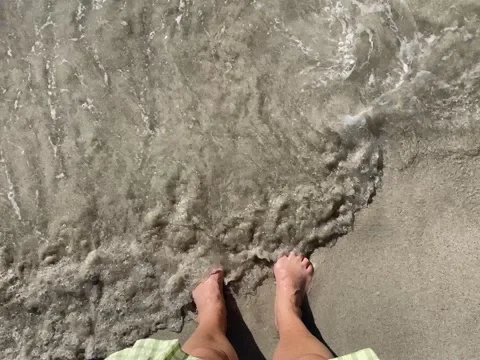 Soft ocean waves lapping water over adult feet Stock-Footage 217686185
