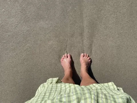 Soft ocean waves lapping water over adult feet Video stock 217686210