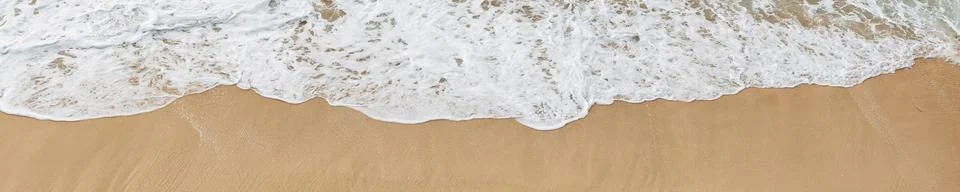 Soft ocean waves roll onto the sandy beach, creating delicate foam patterns.. Stock Photos