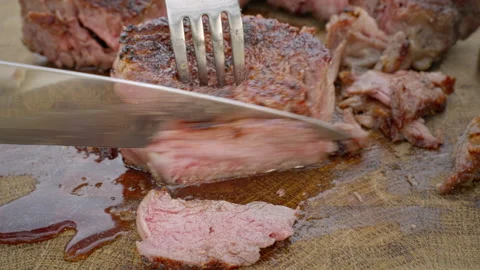 The soft part of the meat, cut from a grilled steak, is cut into pieces with a Video stock 264161841