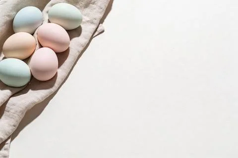 Soft pastel colored Easter eggs arranged on a linen cloth with natural light Stock Photos