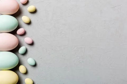 Soft pastel colored Easter eggs arranged on a textured gray background Foto stock