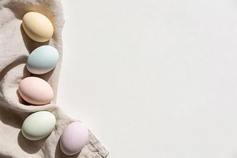Soft pastel Easter eggs arranged on a textured linen cloth with natural light Stock Photos