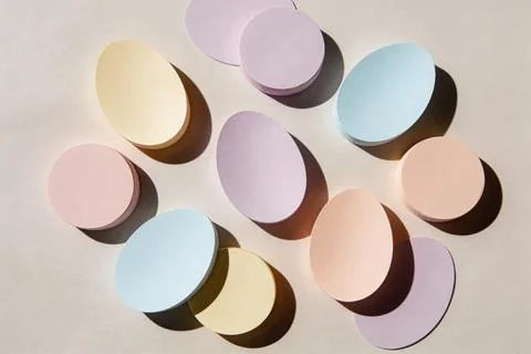 Soft pastel Easter eggs arranged in a scattered pattern on a neutral backgrou Stock Photos