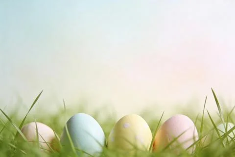 Soft pastel Easter eggs nestled in fresh green grass with a blurred backgroun Stock Photos