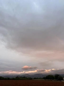 Soft pastel sunset sky over rural landscape with mountains Stock Photos