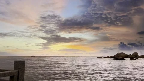 Soft Pastel Twilight Sky Over Calm Ocean with Granite Rocks and Pier Structure Vídeo Stock 320034965
