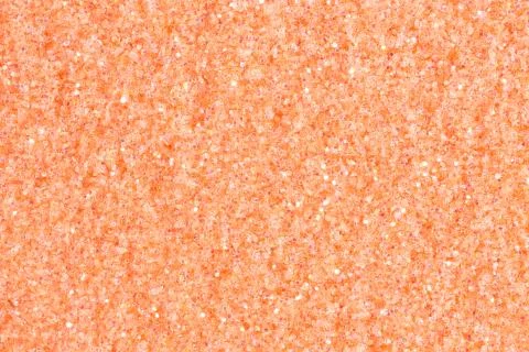 Soft peach glitter background on macro. Light orange glitter texture. Stock Photos