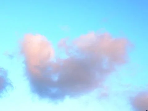 Soft pink cloud floats above pale blue sky 스톡 사진