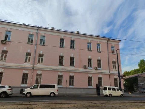 A soft pink facade with rows of rectangular windows, some featuring protective Foto stock